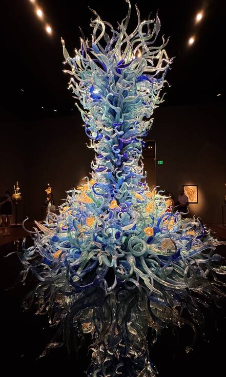 Glaskunst in tinten blauw met een weerspiegeling op de ondergrond
