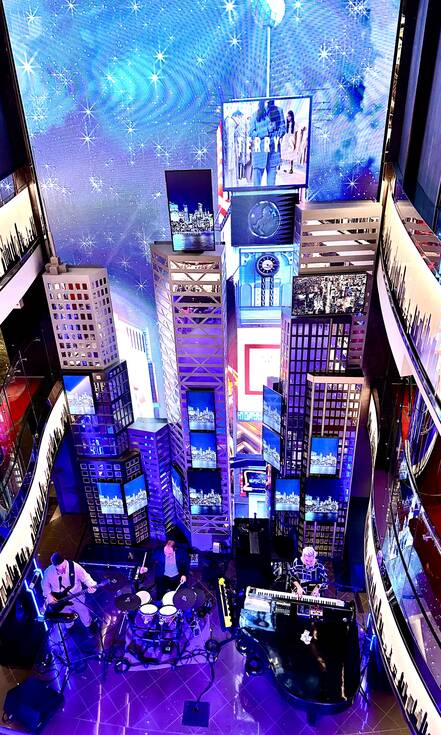Op de foto zie je het schip van binnen. Je kijkt van boven naar beneden op een band, het podium lijkt op Times Square met blauwe en paarse lichten.